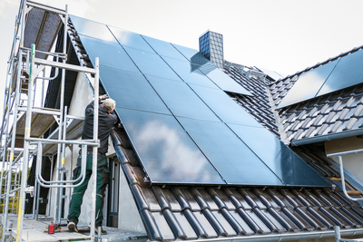 Person installing solar panels at the construction site of a house