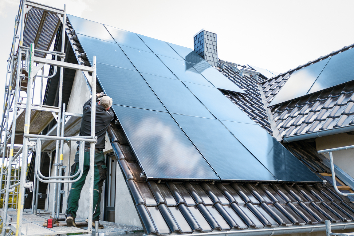 Person installing solar panels at the construction site of a house